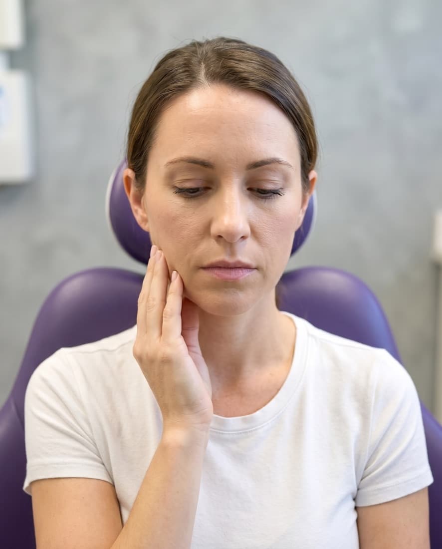 A patient resting her fingers against a tender jaw