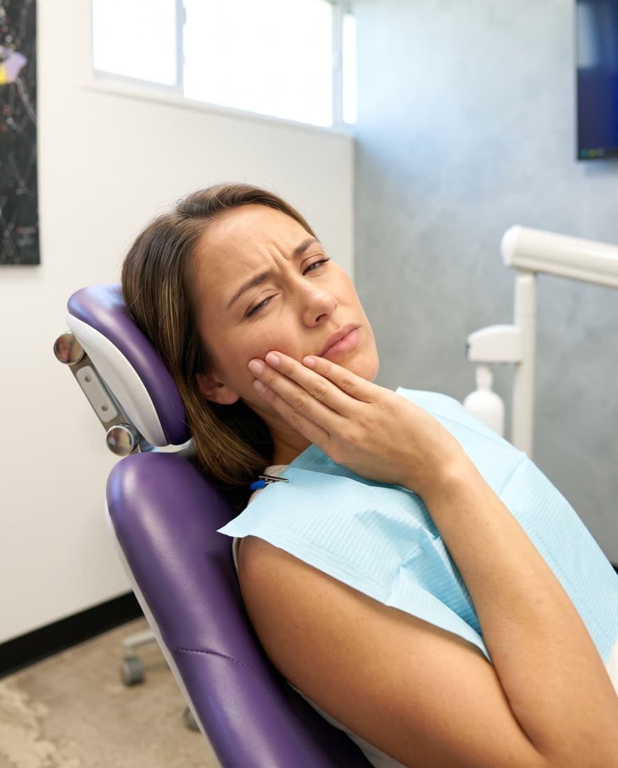 A patient in the chair holding her cheek in pain